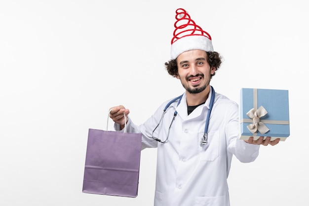 Vue de face d'un médecin de sexe masculin tenant des cadeaux sur un mur blanc