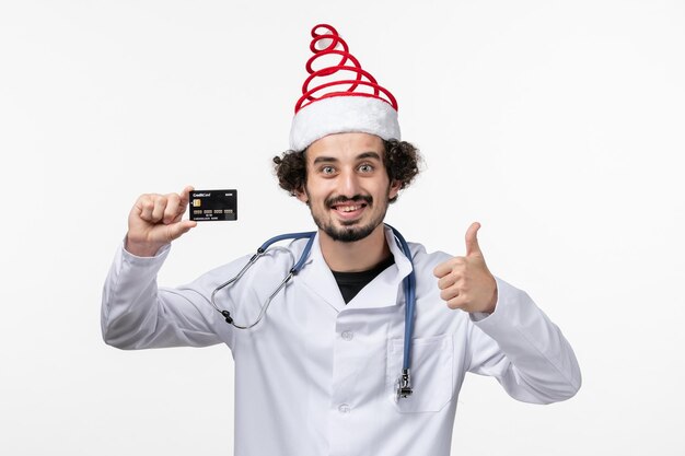 Vue de face d'un médecin de sexe masculin tenant une carte bancaire sur un mur blanc