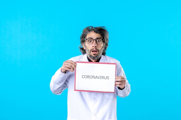 Vue de face médecin de sexe masculin tenant un coronavirus écrivant sur bleu
