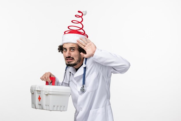 Vue de face d'un médecin de sexe masculin tenant une trousse de premiers soins sur un mur blanc