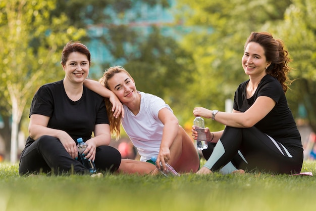 Vue de face meilleurs amis assis sur l'herbe tout en portant des vêtements de sport