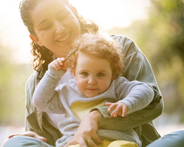 Vue de face de la mère lgbt à l'extérieur dans le parc avec son enfant