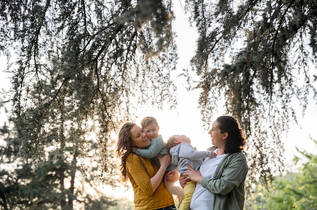 Vue de face des mères lgbt à l'extérieur dans le parc avec leurs enfants