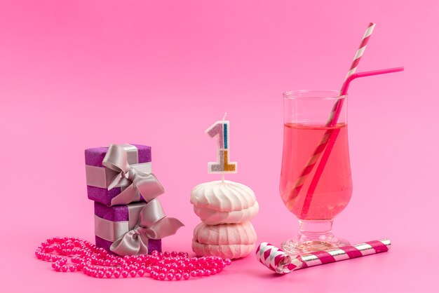 Une vue de face des meringues et des boîtes avec boisson sur rose, couleur biscuit gâteau