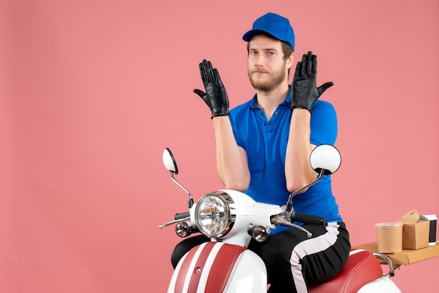 Vue de face messager masculin en uniforme bleu sur un service de livraison de vélo de nourriture de couleur rose travail de restauration rapide