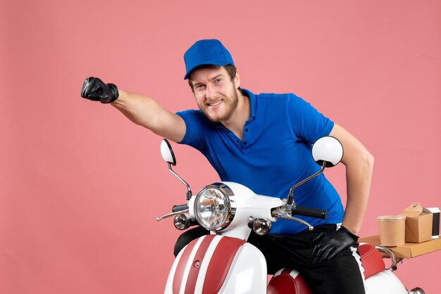 Vue de face messager masculin en uniforme bleu sur un vélo de couleur de service de restauration rapide de livraison de travail rose