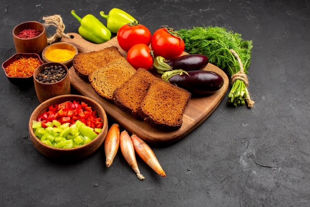 Vue de face miches de pain noir avec assaisonnements tomates et aubergines sur fond sombre salade santé repas mûr régime végétal