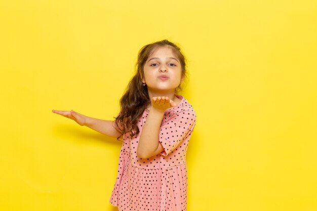 Une vue de face mignon petit enfant en robe rose envoi de baiser