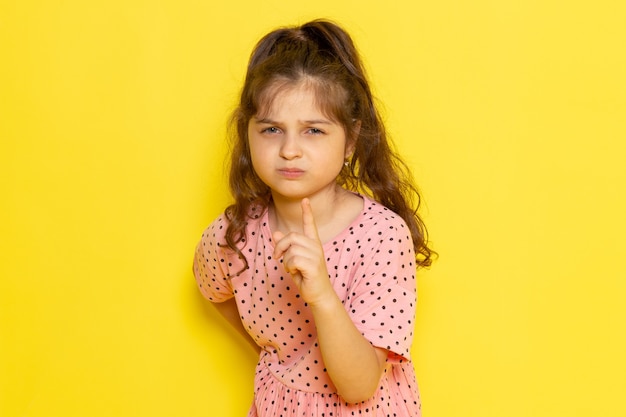 Une vue de face mignon petit enfant en robe rose avec expression menaçante