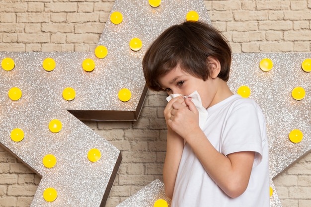 Une vue de face mignon petit enfant en t-shirt blanc jean foncé sur l'étoile conçu stand jaune et fond clair