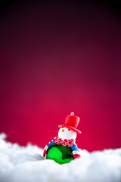 Vue de face mini bonhomme de neige sur fond rouge foncé