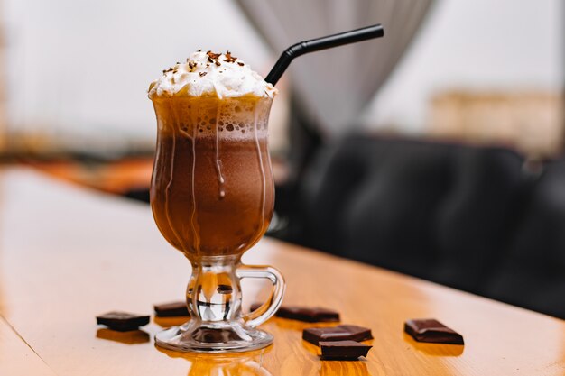 Vue de face mokachino avec crème fouettée et chocolat sur la table