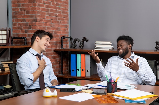 Vue de face des négociations commerciales deux chefs d'entreprise souriants travaillant au bureau