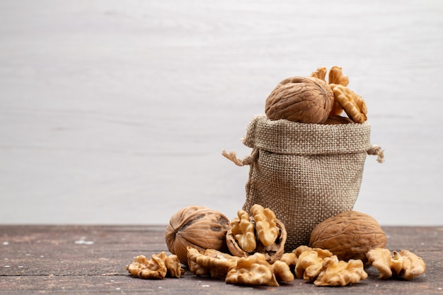 Vue de face de noix entières fraîches dans des coquilles et nettoyées sur gris, snack noix de noix