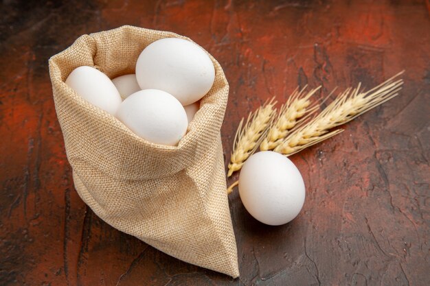 Vue de face des œufs de poule à l'intérieur d'un petit sac sur une surface sombre