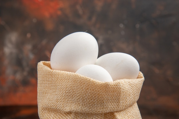 Photo gratuite vue de face des œufs de poule à l'intérieur d'un petit sac sur une surface sombre