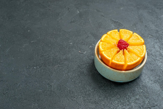 Vue de face d'oranges fraîches tranchées à l'intérieur de la plaque sur fond sombre jus de fruits frais aux agrumes