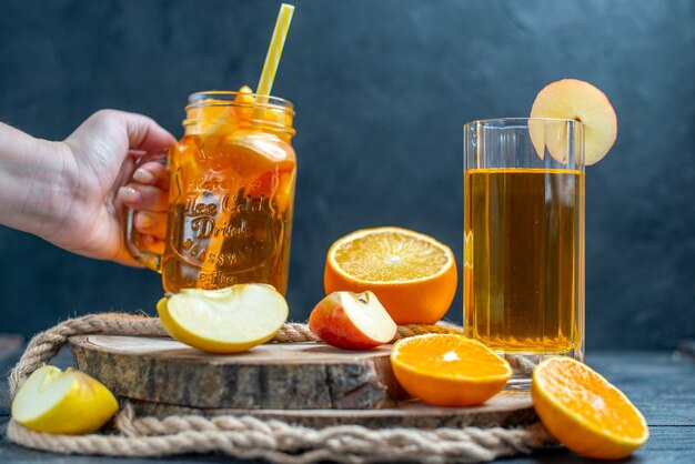 Vue de face des oranges et des pommes coupées en cocktail sur planche de bois dans l'obscurité