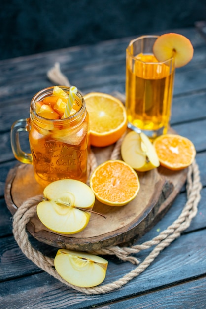 Vue de face des oranges et des pommes coupées en cocktail sur planche de bois dans l'obscurité