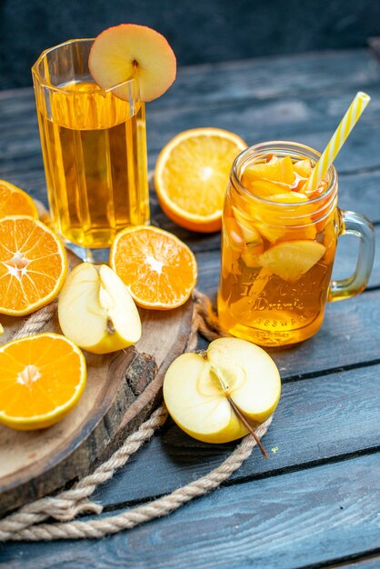 Vue de face des oranges et des pommes coupées en cocktail sur planche de bois dans l'obscurité