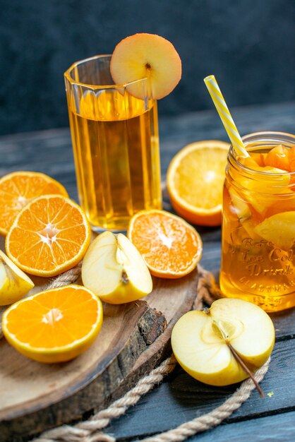 Vue de face des oranges et des pommes coupées en cocktail sur planche de bois dans l'obscurité