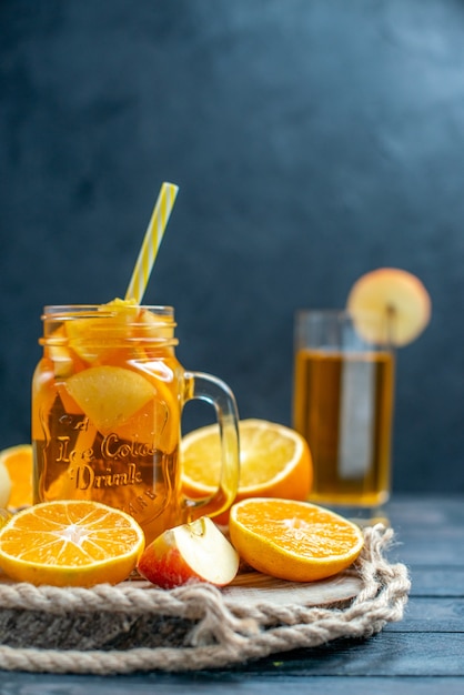 Vue de face des oranges et des pommes coupées en cocktail sur planche de bois dans l'obscurité