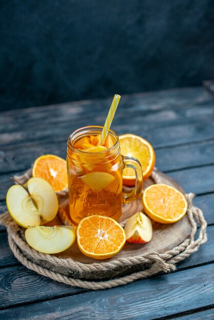 Vue de face des oranges et des pommes coupées en cocktail sur planche de bois dans l'obscurité