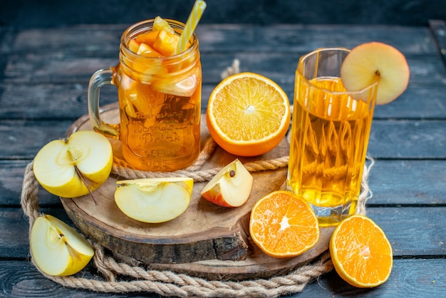 Vue de face des oranges et des pommes coupées en cocktail sur planche de bois dans l'obscurité