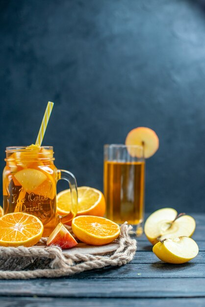 Vue de face des oranges et des pommes coupées en cocktail sur planche de bois dans l'obscurité