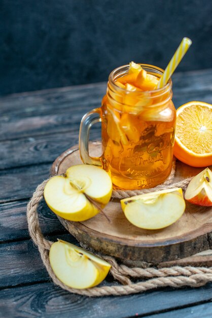 Vue de face des oranges et des pommes coupées en cocktail sur planche de bois dans l'obscurité