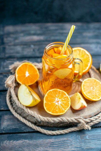 Vue de face des oranges et des pommes coupées en cocktail sur planche de bois dans l'obscurité