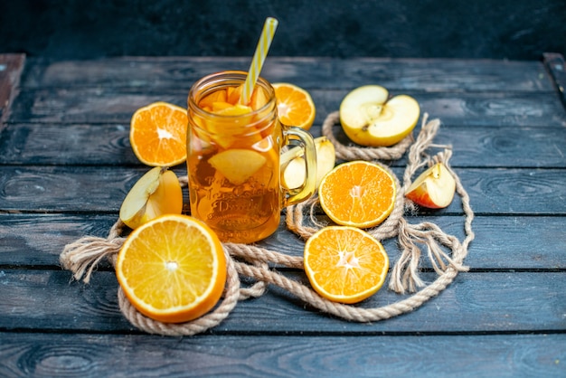 Vue de face des oranges et des pommes coupées en cocktail sur planche de bois dans l'obscurité