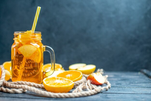 Vue de face des oranges et des pommes coupées en cocktail sur planche de bois dans l'obscurité