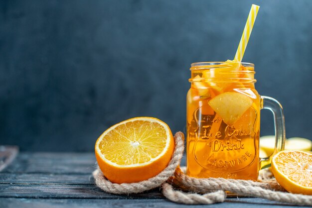 Vue de face des oranges et des pommes coupées en cocktail sur planche de bois dans l'obscurité