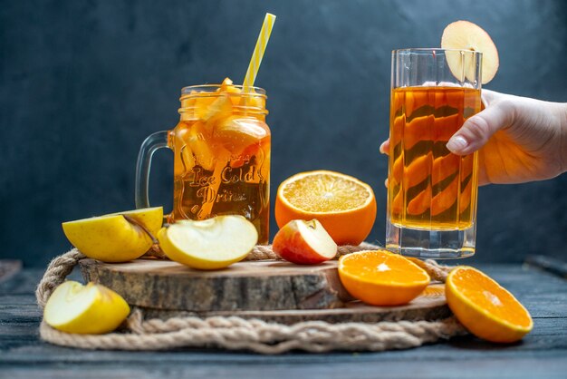 Vue de face des oranges et des pommes coupées en cocktail sur planche de bois dans l'obscurité