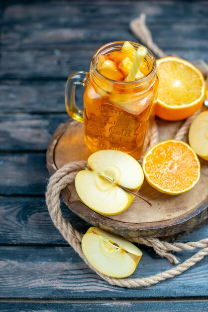 Vue de face des oranges et des pommes coupées en cocktail sur planche de bois sur fond isolé sombre