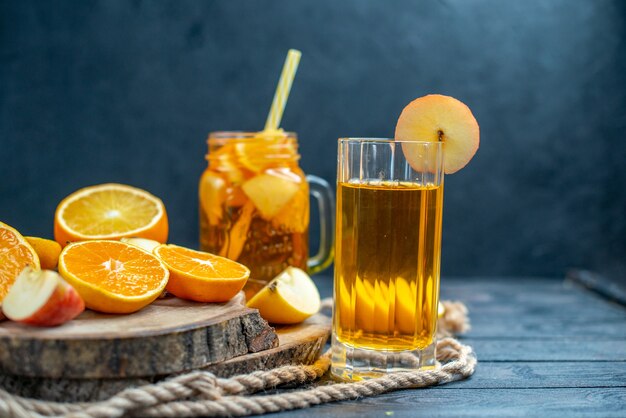 Vue de face des oranges et des pommes coupées en cocktail sur planche de bois sur fond isolé sombre