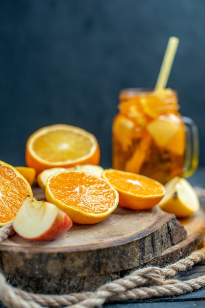 Vue de face des oranges et des pommes coupées en cocktail sur planche de bois sur fond isolé sombre