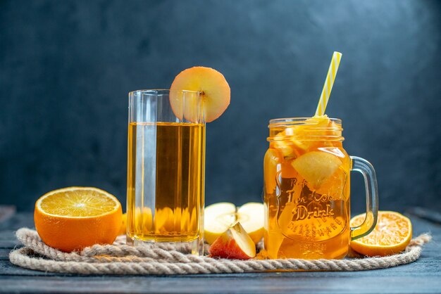 Vue de face des oranges et des pommes coupées en cocktail sur planche de bois sur fond isolé sombre