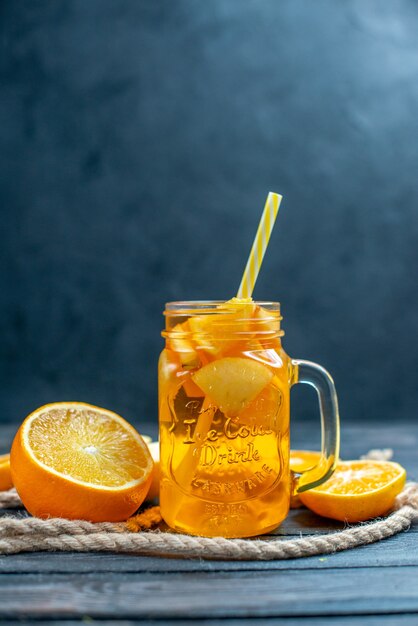 Vue de face des oranges et des pommes coupées en cocktail sur planche de bois sur fond isolé sombre