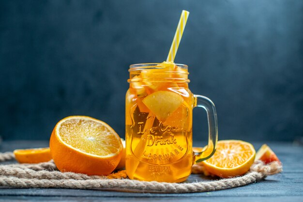 Vue de face des oranges et des pommes coupées en cocktail sur planche de bois sur fond isolé sombre