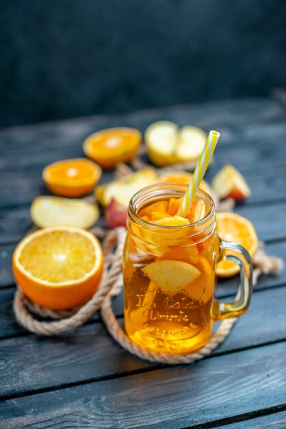 Vue de face des oranges et des pommes coupées en cocktail sur planche de bois sur fond isolé sombre