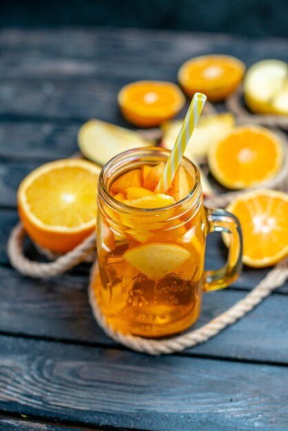 Vue de face des oranges et des pommes coupées en cocktail sur planche de bois sur fond isolé sombre