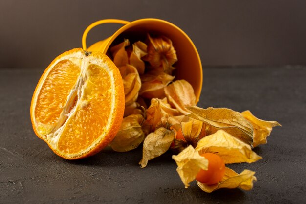 Une vue de face oranges tranchées avec fruits ronds orange pelés répartis sur gris
