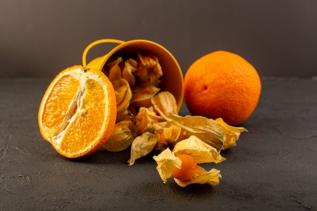 Une vue de face oranges tranchées avec fruits ronds orange pelés répartis sur gris