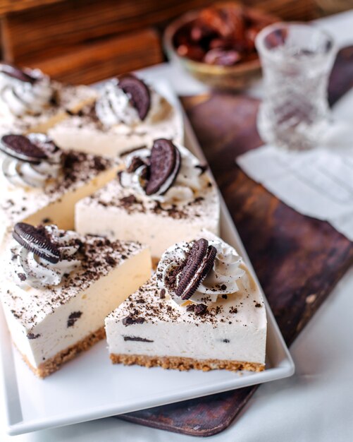 Vue de face oreo cheesecakes savoureux délicieux à l'intérieur de la plaque blanche sur le sol brun