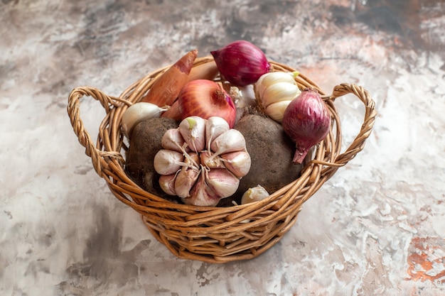 Vue de face panier avec légumes ails oignons et betteraves sur fond clair