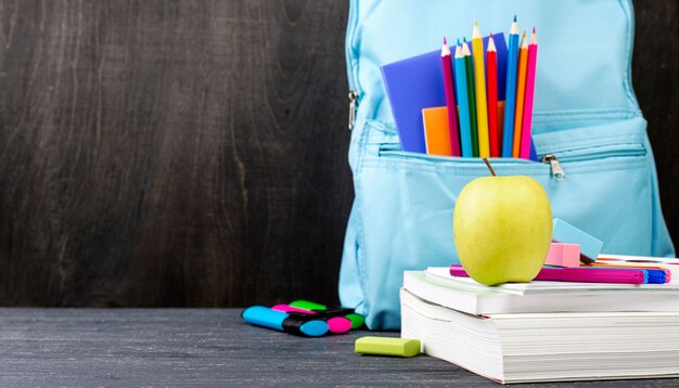 Vue de face de la papeterie de retour à l'école avec des crayons colorés et pomme