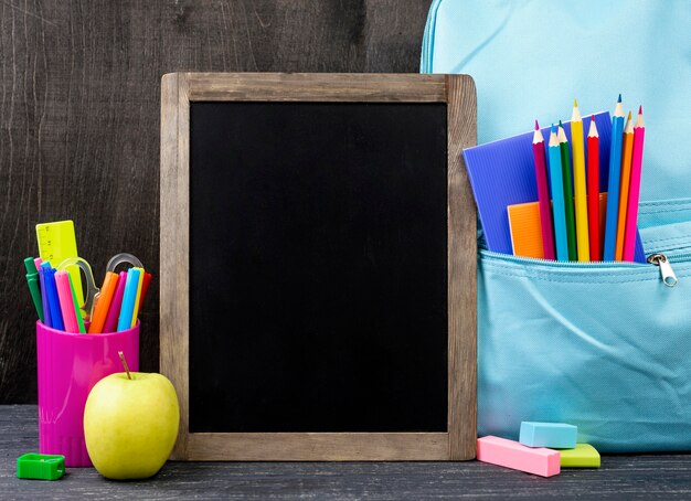 Vue de face de la papeterie de retour à l'école avec des crayons colorés et un tableau noir