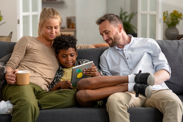 Vue de face parents et enfant assis sur un canapé